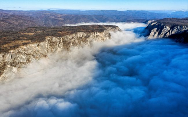 A Duna Szerbia és Románia között. Itt, a szerb oldalon a Djerdap Nemzeti Park terül el partján, szemben pedig a romániai Vaskapu Természetvédelmi terület. Közismertebb nevein ez a hely a Vaskapu vagy Kazán-szoros. A két ország mezsgyéjén, Európa leghosszabb szurdokában szűkül össze az addigra hatalmasra duzzadt folyam. Az első reggelen sikerült megörökíteni a folyót, de a másodjára a köd keresztülhúzta a számításaimat. Viszont teremtett egy teljesen új helyzetet. Így lett nevéhez méltó a hely. Ott, valahol a gomolygó füstszerű köd alatt kavarog, kanyarog titokzatosan a vad víz, mint egy üstben, katlanban. A meredek mészkő sziklafalak 150 méternyire szűkítik, cserébe ezért viszont 82 méter mély a víz- ez a világ legnagyobb folyómélysége.